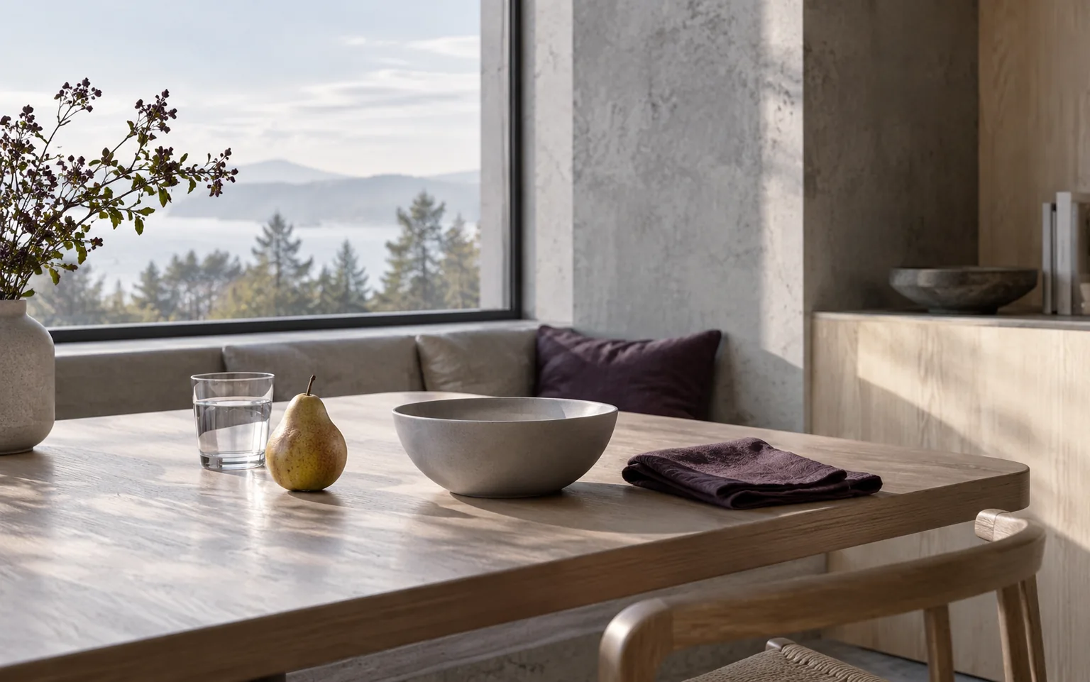 An empty ceramic bowl, pear and water glass in a cool breakfast alcove.